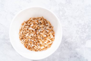 Beyaz bir seramik kasede kızarmış hindistan cevizi taneleri..