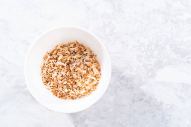 Beyaz bir seramik kasede kızarmış hindistan cevizi taneleri..