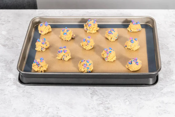 Chilled cookie dough scoops on the baking sheet to bake unicorn chocolate chip cookies.