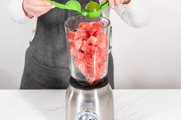 Blending ingredients in a kitchen blender to prepare frozen watermelon margarita.