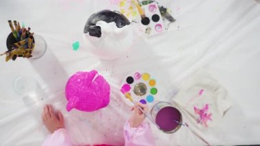 Küçük kız Cadılar Bayramı balkabağını akrilik boyayla boyuyor.