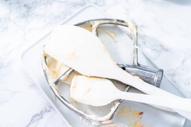 Kirli mikser küreği ve spatula beyaz bir tabakta kek pişirdikten sonra.