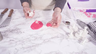 Adım adım. Mermer tezgahın üstünde pembe fondanla kar tanelerini keserek..