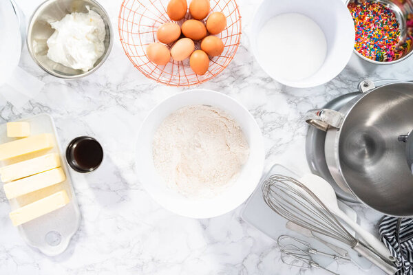 Ingredients to bake funfetti cake with colorful sprinkles.