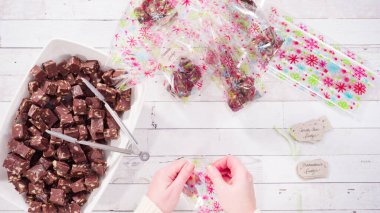 Düz yatıyordu. Adım adım. Ev yapımı macadamia şekerlemesi küçük hediye paketlerine konuyor..