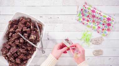 Düz yatıyordu. Adım adım. Ev yapımı macadamia şekerlemesi küçük hediye paketlerine konuyor..