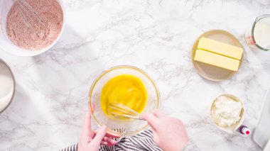 Düz yatıyordu. Adım adım. Kırmızı kadife kek pişirmek için bardakta ıslak malzemeler karıştırıyorum..