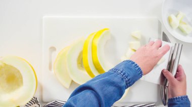 Adım adım. Düz yatıyordu. Beyaz kesme tahtasında kaygan altın çiğ taneli kavun.