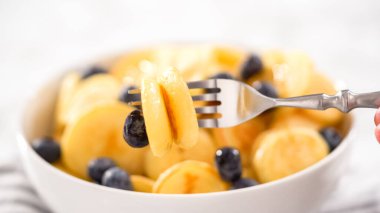 Adım adım. Taze yapılmış mini krep gevreği ve beyaz kasede taze yaban mersini..