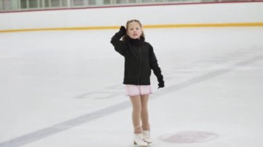 Küçük kız buz pistinde artistik patinaj yapıyor..