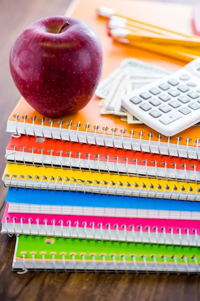 Cuadernos, lápices, calculadora, efectivo y manzana Material escolar —  Fotos de Stock