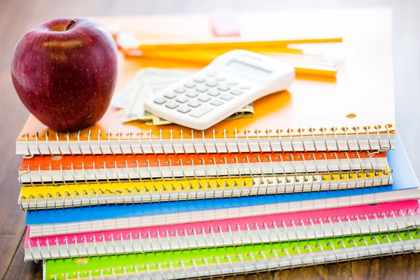 Carnets, crayons, calculatrice, argent comptant et pomme Fournitures scolaires — Photo