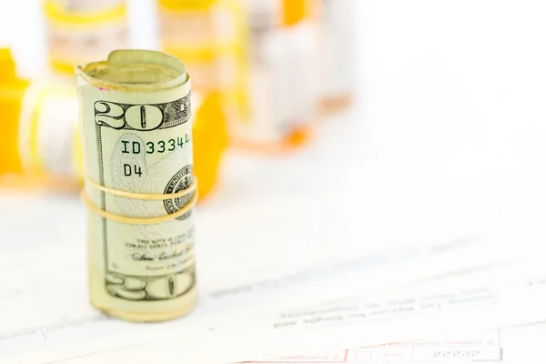 Income tax return with folded cash and pills — Stock Photo, Image