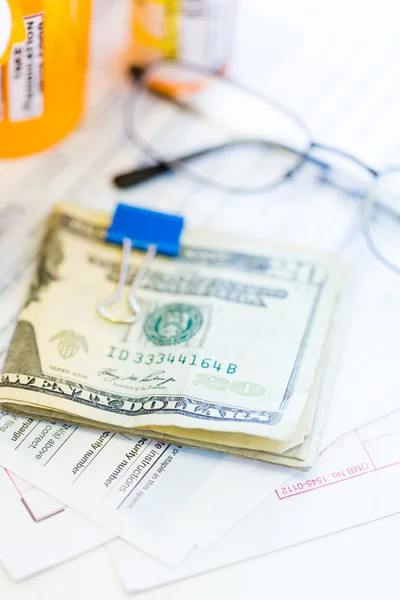 Income tax return with folded cash and pills — Stock Photo, Image