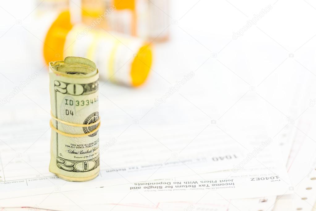 Income tax return with folded cash and pills
