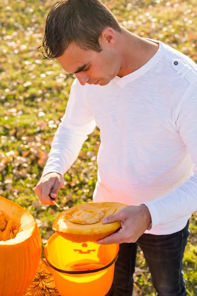 Homme sculptant de grandes citrouilles orange — Photo