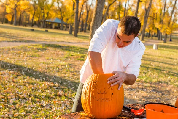 Hombre tallando grandes calabazas naranjas — Foto de Stock