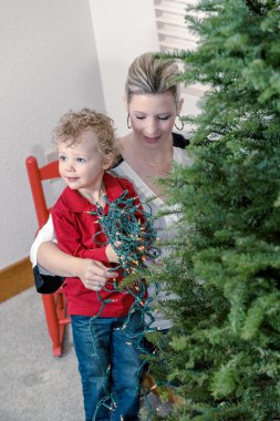 Anne ve oğul Noel ağacı süslüyorlar.