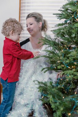 Anne ve oğul Noel ağacı süslüyorlar.