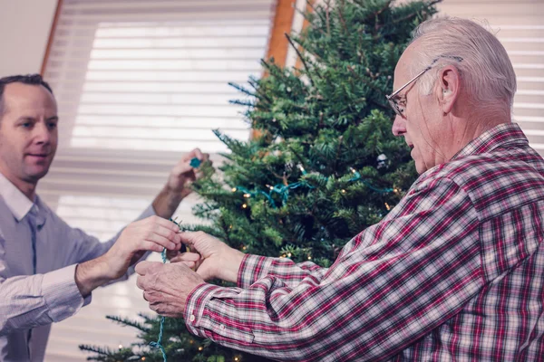 Grandfather decorating Christmas tree — Stock Photo, Image