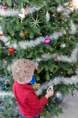 Noel ağacı süsleyen küçük çocuk.