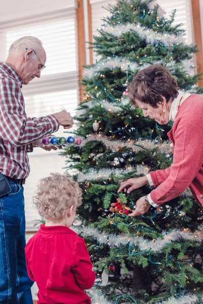 Abuelos con nieto decorando árbol de Navidad — Foto de Stock