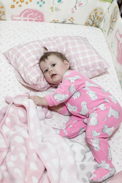 Маленькая девочка играет в своей кроватке — стоковое фото