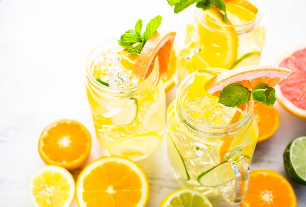 Water with fresh citrus fruits and ice — Stock Photo, Image