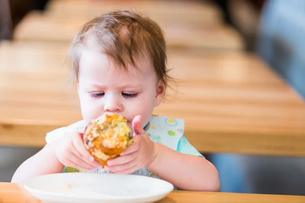 Liten flicka äter muffin — Stockfoto