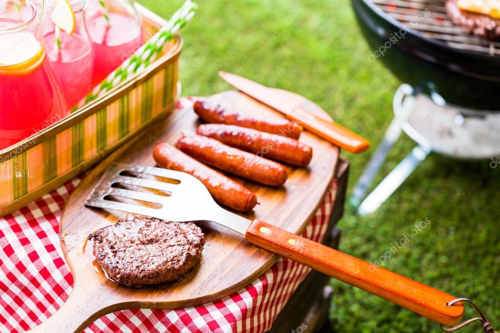 Summer picnic, hot dogs, lemonade and hamburger patties Stock Photo by
