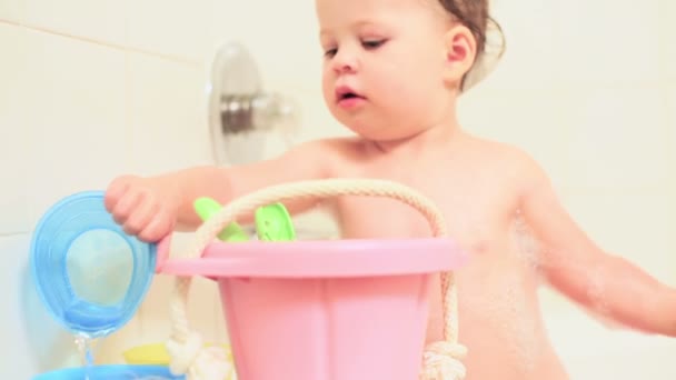 Маленька дівчинка купається в ванні з іграшками — стокове відео