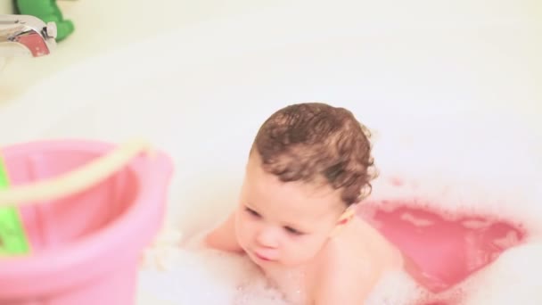 Liten flicka badar i ett bad med leksaker — Stockvideo