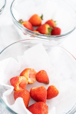 Taze yıkanmış ve kurutulmuş çilekler kağıt havluyla kaplı cam bir kasede dikkatlice düzenlenir. Atıştırmaya ya da daha fazla kullanılmaya hazır hale getirilir..