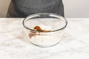 Cam bir kasede aromatik baharatlarla harmanlanmış unlu unlu zencefilli kurabiye yapmaya hazır. Karışımda tarçın, zencefil ve karanfil var.