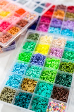Beyaz bir masaya yerleştirilmiş çeşitli kil boncuk kutuları yaratıcı çocukların el sanatları projesini bekliyor..