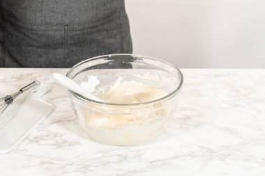Mermer bir yüzey üzerinde karıştırma kâsesi. Kremalı, sade, beyaz, sarımsı bir buzlanma mükemmel bir şekilde çırpılmaya hazır. Tatlılar üzerinde borulamaya ya da yaymaya hazır..