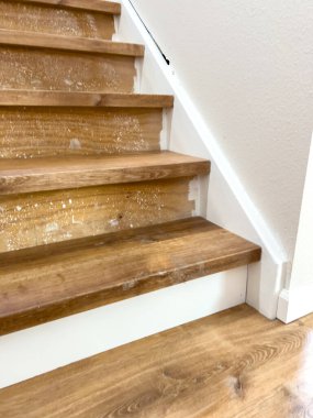 This stairway is mid-installation with several laminate steps in place. Adhesive is visible beneath the top stair, and the room is illuminated by indoor lighting.