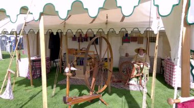 Sedalia, CO, Usa-Eylül 20, 2025 - Slow Motion - Tarihi bir kampta ahşap dönen tekerlek ve el yapımı eşyalar sergilenen bir çadırın yakın görüntüsü. Halatlar ve direkler girişi çerçeveler.