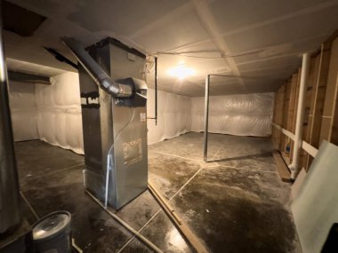 Parker, Colorado, ABD-1 Haziran 2025 - Beton döşeme ve beyaz yalıtımlı temiz bir emekleme alanı merkezi havalandırma ünitesini kanal işçiliğiyle kapatır. Mekanik sistem ısıtma ve hava için kurulur