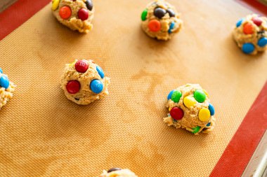 Parker, Colorado, ABD-1 Temmuz 2025 - Fıstık ezmeli kurabiye hamuru Scoops kırmızı, yeşil ve mavi şekerler eşit aralıklarla pişirme tepsisinde. Silikon paspas pürüzsüz, profesyonel bir...