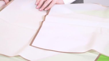 Yeşil bir yüzey üzerinde pembe süslemeli elleri peş peşe saran örtülü çarşaflar. Kurulum, buketi en üste yerleştirmek için hazırlanır..