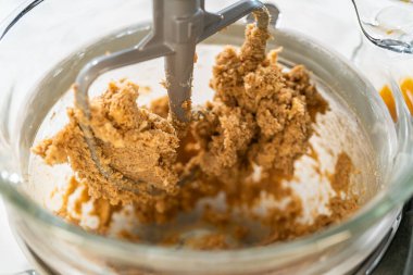 Tereyağı ve esmer şekeri karıştıran bir standın yakın plan yan görüntüsü Amber Zencefilli Kurabiye Kurabiyesi için hamur karışımında yumuşak bir doku oluşturuyor. Işık ve hava yoğunluğu...