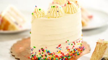 Doğum günü pastası son derece yakın planda, nemli sünger katmanları, çırpılmış krema ve kenardan hafifçe akan canlı bir meyve ile gösterilir..