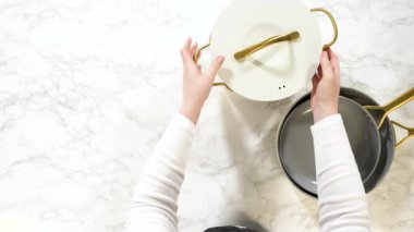 Temiz beyaz mermer bir yüzey çerçeveyi doldurur, bu da mutfak sekansının başlangıcını ya da sonunu gösterir. Genel çekim ürün yerleştirme veya görsel karşıtlık için yer sağlar.