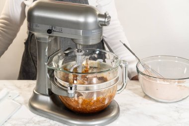 Çikolatalı Zencefilli Kurabiye Hamuru 'nun malzemelerini karıştırmak için kullanılan bir tezgah. Karıştırma işlemi devam ediyor, zengin ve pürüzsüz bir kurabiye hamuru yaratıyor.