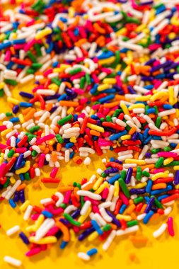 Dikey bir düzende sarı arkaplanda kalın renkli serpintiler görülüyor. Dikey bileşim dokuyu ve renk yoğunluğunu vurgular.