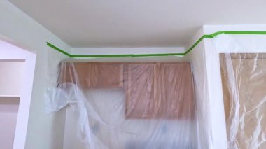 Süpürge, Colorado, ABD-12 Mayıs 2024-Slow motion-An iç dekorasyon sahnesi plastik kaplama ve maskeleme bandıyla hazırlanmış odaları gösteriyor. Alan boyamaya hazır ya da daha ileri.
