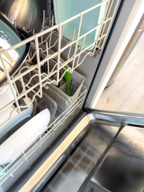 Parker, Colorado, ABD-27 Nisan 2025 - Temiz tabak, tabak ve cam kaplarla dolu bir bulaşık makinesinin yukarıdan aşağı görüntüsü. Görüntü, parlak bir ev mutfağında düzgünce istiflenmiş açık bir aygıtı yakalıyor.