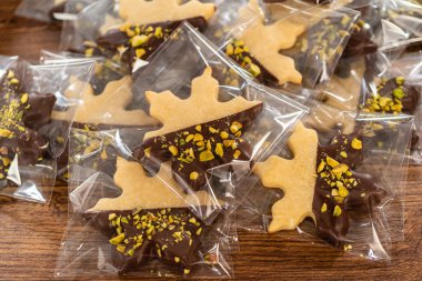 Dikkatlice paketlenmiş Noel kurabiyeleri, çikolataya batırılmış ve şeffaf selofan ambalajla sunulmuş, bayram hediyesi olarak mükemmel..