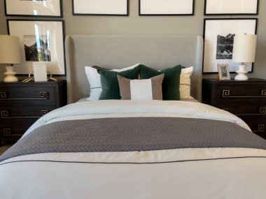 Parker, Colorado, ABD-19 Haziran 2025 - Lüks yatak odası, yatak başlığı, yeşil ve beyaz yastıklar, çerçeveli sanat ve uyumlu lambalar. Genel tonu zarif ve dengeli..